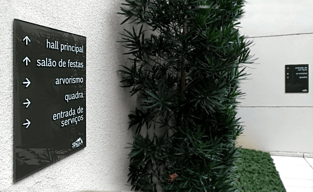 Placas de sinalização direcional instalada em área externa de condomínio, com acabamento em acrílico e design minimalista. Esta placa de sinalização para condomínio orienta o fluxo de pessoas com clareza, reforçando a organização visual e a experiência do usuário no ambiente.