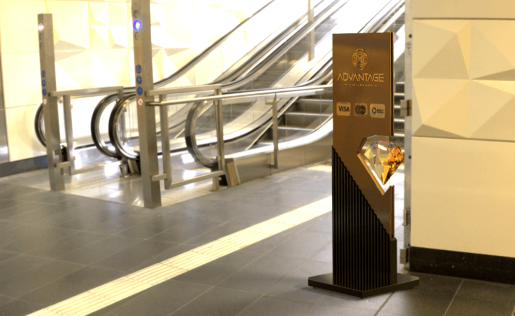 Totem de design estratégico assinado pela Spacca para o novo rebranding da Advantage VIP Lounge, posicionado em área de circulação no aeroporto. A peça combina soluções visuais de alto impacto com acabamentos premium, como, estrutura vertical com ripado e elementos em latão, logotipo em formato de diamante facetado tridimensional, alinhando branding e funcionalidade ao posicionamento de mercado da marca.