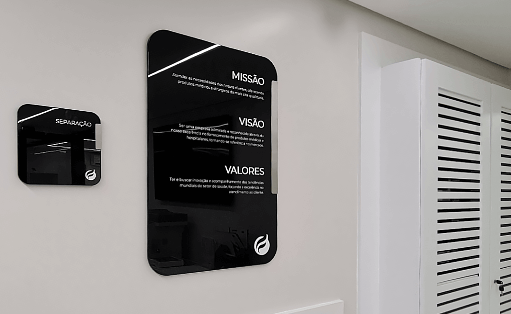 Placa de sinalização institucional aplicada no ambiente corporativo da Fixen Group, empresa especializada em soluções médicas e hospitalares. O conjunto inclui duas placas de sinalização interna, sendo uma com os princípios de missão, visão e valores, reforçando a identidade visual da marca. Também classificada como placa de sinalização para hospital, a peça comunica de forma estratégica e integrada, consolidando presença e funcionalidade no ambiente empresarial.
